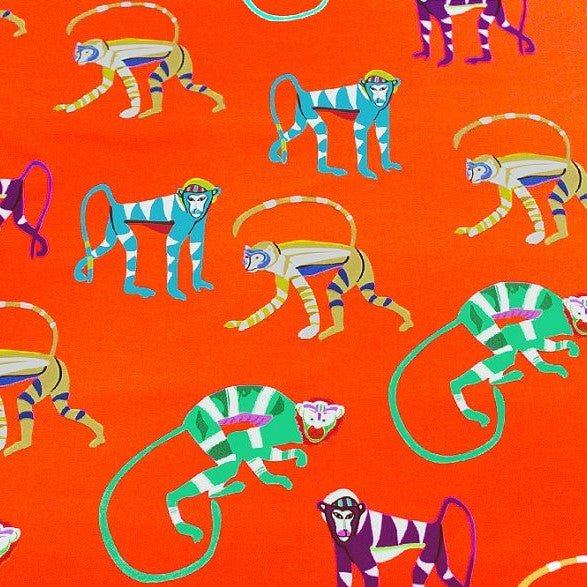 A flat sample of orange monkey printed spandex.
