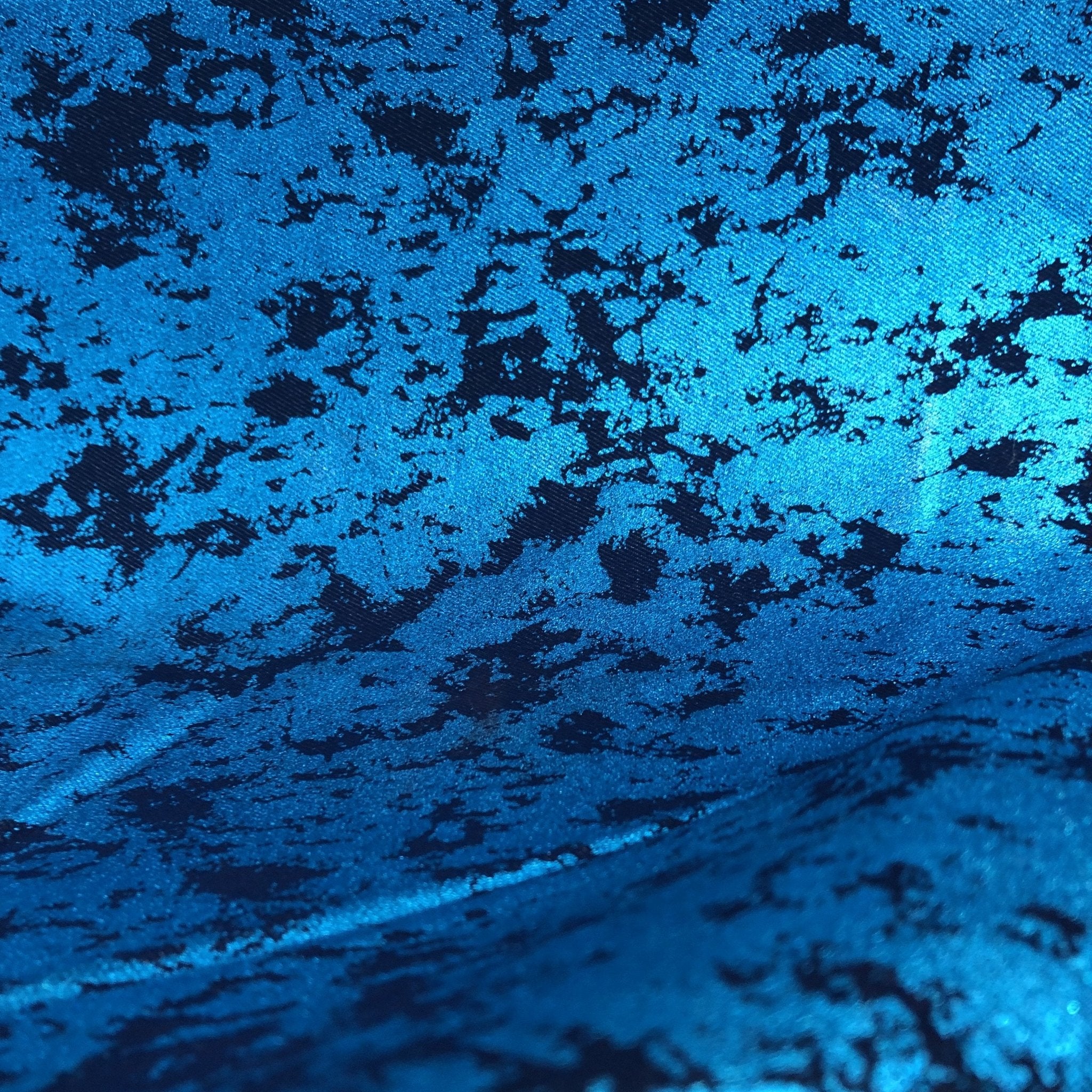 A draped sample of jolt foiled stretch faux denim in the color turquoise.