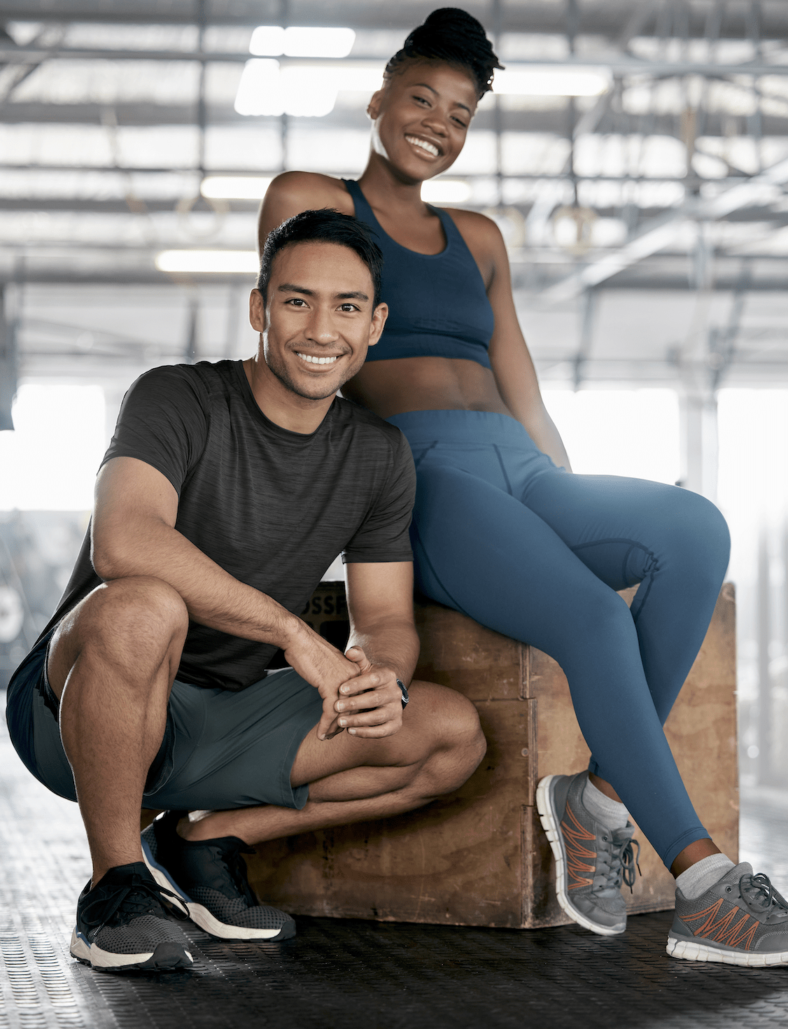 Two people sitting on a bench in an indoor gym.