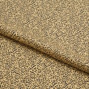 A yard of baby cheetah pattern printed spandex fabric displaying a beige ground color with a small black cheetah print.