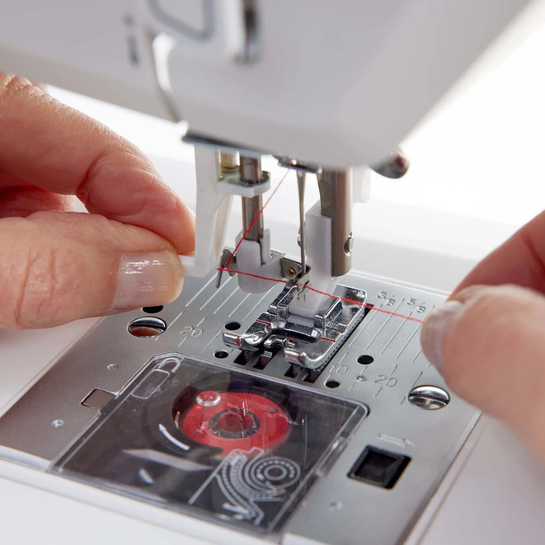 Close-up of a HUSQVARNA VIKING ONYX 25 sewing machine with a hand adjusting the needle.