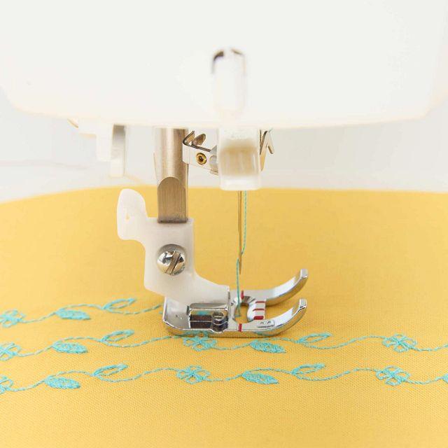 An image of the HUSQVARNA VIKING ONYX 30 sewing machine embroidering on yellow fabric.