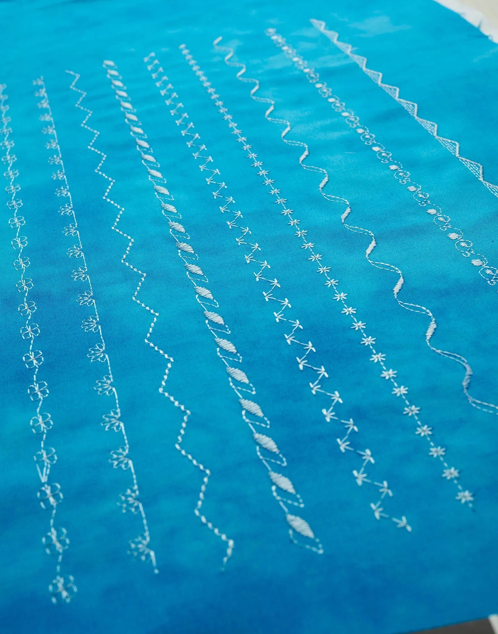 Close-up of blue fabric with white embroidery patterns