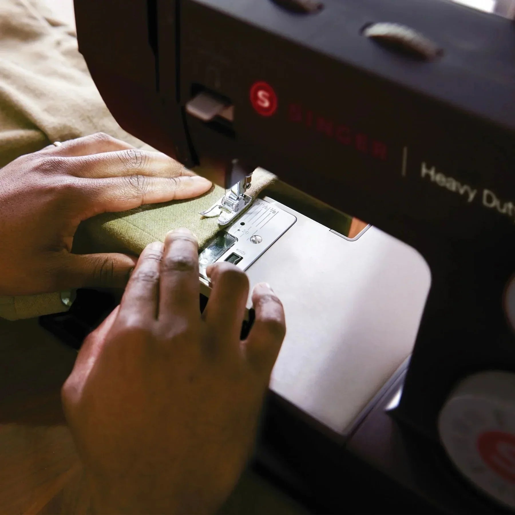 A person sewing fabric with the Singer Heavy Duty 4432 Black Sewing Machine.