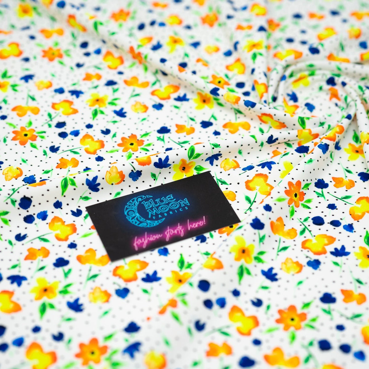 Swirled sample shot of Watercolor Flowers and Black Dots Printed Spandex with a Blue Moon Fabrics standard size business card laid on top of the print for pattern sizing.