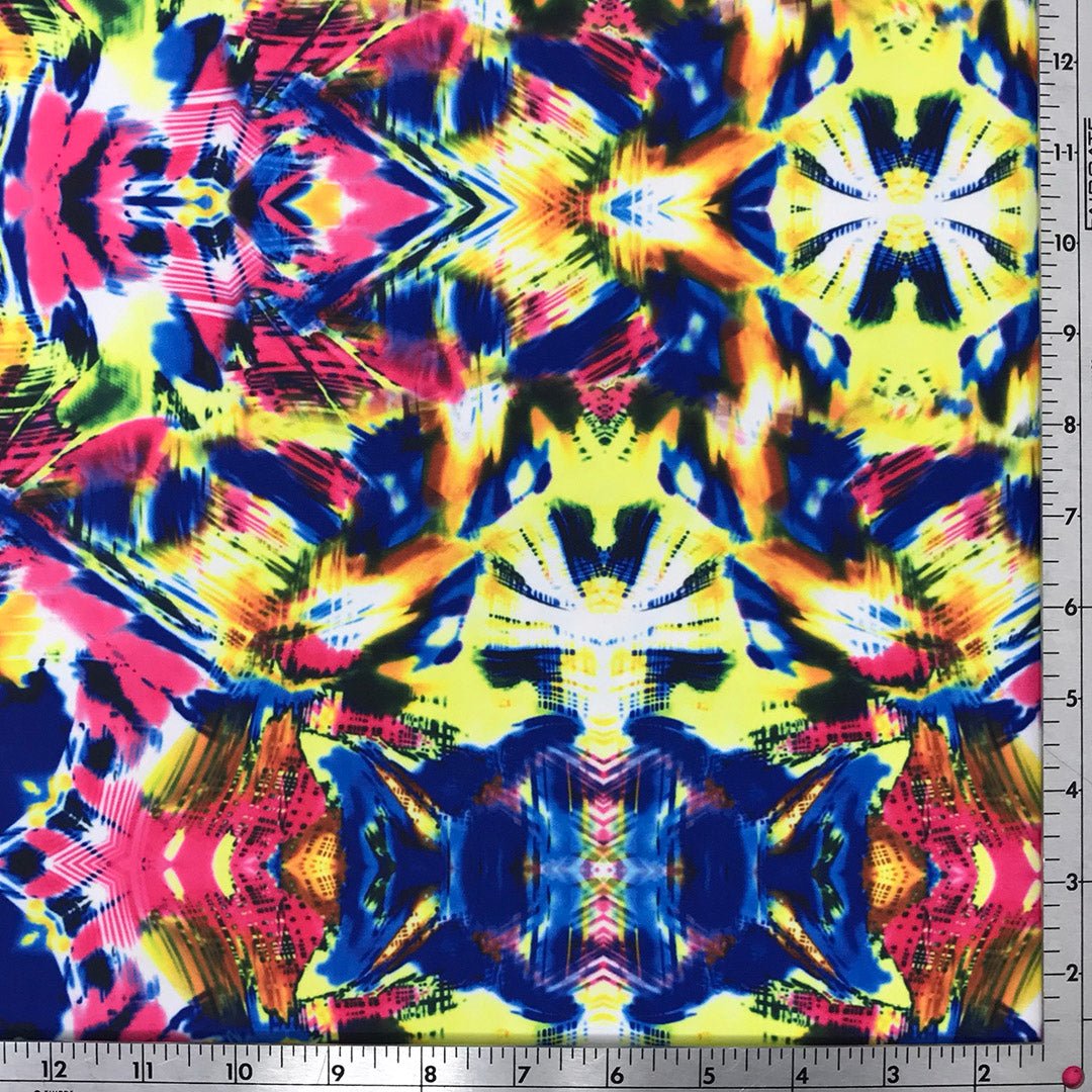A flat sample of primary kaleidoscope printed spandex and a ruler for scale.